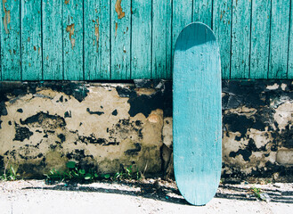 Green wooden skateboard on deteriorated wall on a sunny day. Skateboarding background, street...