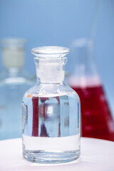 Reagent bottle with glass stopper, blue background, pharmacy or medicine concept, with copy space