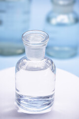 Reagent bottle with glass stopper, blue background, pharmacy or medicine concept, with copy space