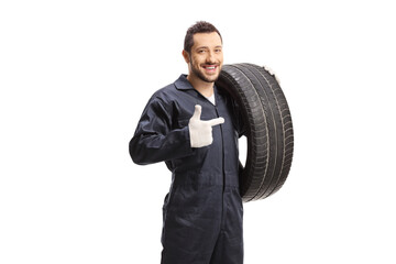 Auto mechanic holding a of car tire and pointing - obrazy, fototapety, plakaty
