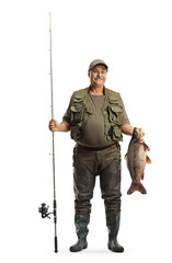 Full length portrait of a happy fisherman in a uniform holding a big carp fish and a fishing rod