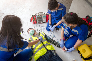 Emergency medical teams are helping unconscious patients using automated external defibrillators (AED) during rescuing unconscious workers at a construction site.