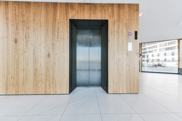 Entrance lobby of luxury apartment building with wooden wall panels and elevator against panoramic windows