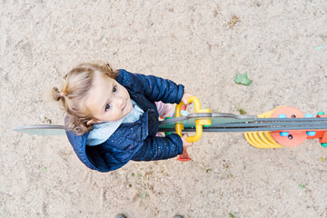 Top view of a toddler girl riding a seesaw