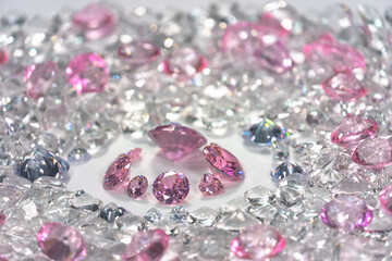 A group of pink diamonds arranged in the middle of white diamonds in a white background..Top view of pink diamonds. white diamonds background