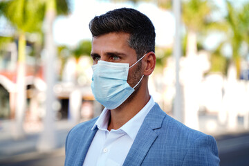 Portrait of handsome man wearing medical blue mask on the face during virus epidemic lockdown.