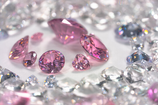 A group of pink diamonds arranged in the middle of white diamonds in a white background..Top view of pink diamonds. white diamonds background