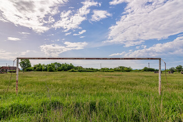 Abandoned soccer field. Overgrown grass and wildflowers on football pitch.