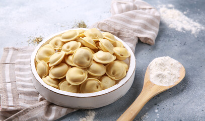 Russian and ukrainian cuisine. The national dish is dumplings in bowl. Dough with minced meat, flour, wooden spoon on a gray background.Background image, copy space