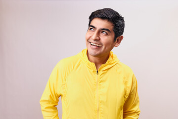 Hombre joven y feliz sorprendido. Modelo aislado en fondo blanco con casaca amarilla