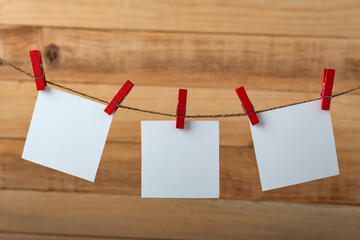 Three white blank note cards hanging with clothespins. Wooden background. Copy space.