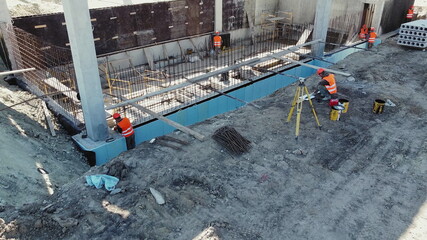 Construction site manager looks at the floor plans. View from a height, a diverse group of professionals working on a construction site. Many different workers on the construction site