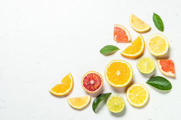 Citrus fruits at white background. Orange, lemon, lime, grapefruit with green leaves. Healthy food. Top view with copy space.