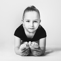 Girl gymnast doing bends to the legs, looking easily at the camera