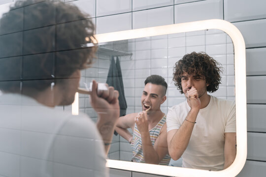 Happy Gay Couple Bonding While Brushing Their Teeth With Bamboo Toothbrush