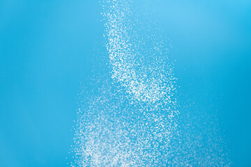 White powder explosion. White powder splash isolated on blue background. Flour sifting on a blue background. Explosive powder white