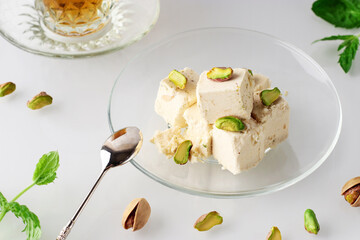Natural vegan product. Halva with pistachios on a glass plate on a light background. Traditional oriental dessert Chekme. Turkish, Arab and Jewish national sweets