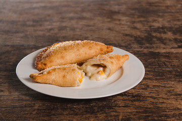 Latin American fried corn and cheese empanadas on top of a wooden table