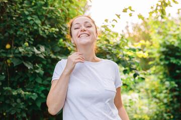 Young woman smiling outdoor. Beautiful brunete girl resting on park or garden green background. Free happy woman at summertime. Freedom happiness carefree happy people concept.