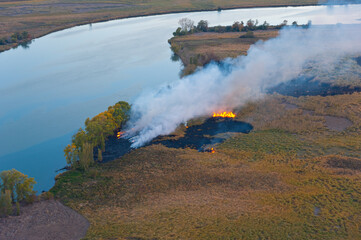 Steppe fire - dry grass is burning on the banks of the river.