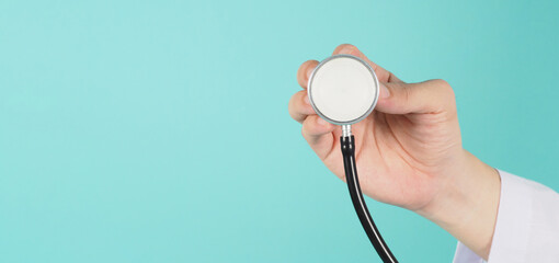 close up of doctor hand holding stethoscope and wear long sleeve gown on mint green or tiffany blue background
