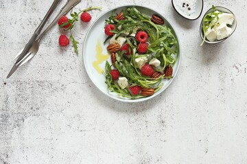 Arugula salad with raspberry, goat cheese and caramelized pecans . Flat layot_ copy space
