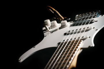 Close up picture of a black electric guitar on a black background.