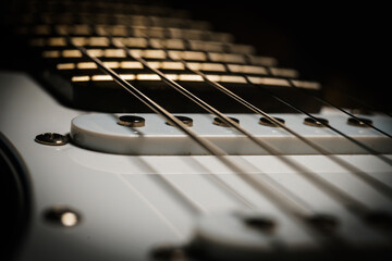 Close up picture of a black electric guitar on a black background.