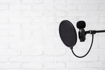 podcast, sound recording and blogging concept - microphone and pop filter over white brick wall