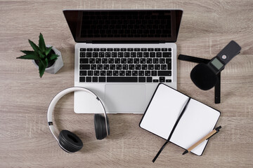 podcast and blogging concept - top view of workplace with laptop, microphone, headphones, open notepad and pen over wooden table background - obrazy, fototapety, plakaty