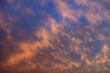 Sunbeams through colorful clouds on blue sky background.