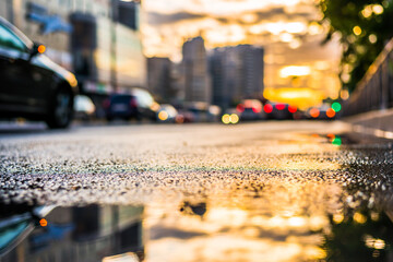 Sun after the rain in the city, view of the cars with a level of puddles on the pavement