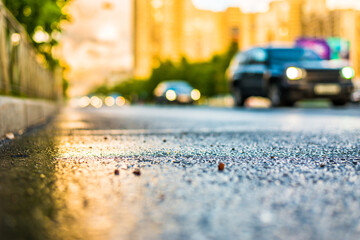 Sun after the rain in the city, view of the approaching cars with a level of puddles on the pavement