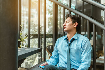 Depressed Businessman sitting on ground stairs suffering emotional stress.