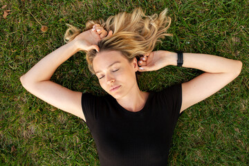 Young blonde woman lying on green grass