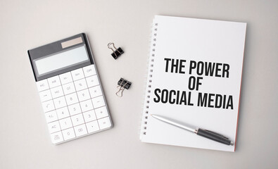 The word THE POWER OF SOCIAL MEDIA a is written on a white background next to a pen ,calculator and reports. Business concept