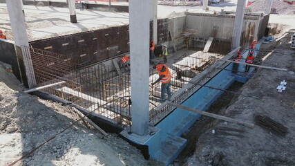 Aerial Flight Over a New Constructions Development Site with Diverse team of Engineers and Architects. Workers work at construction site reinforced concrete structures. Modern monolithic construction