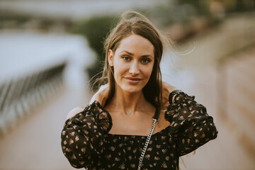 Young long hair brunette woman walking on the riverside
