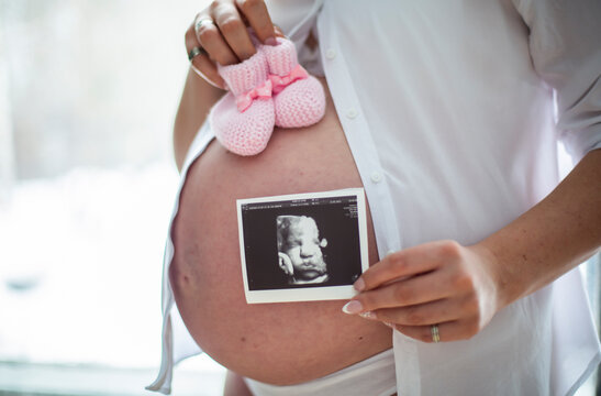  pregnant woman eighth ninth month of pregnancy holding an ultrasound picture of a child