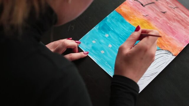 She demonstrates the mental image of the psyche in the drawing. focus of attention of the individual. A woman patient paints a drawing with watercolors during a therapy session. 