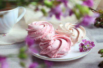 Pink fruit marshmallow on a white saucer with pink flowers, bokeh, close-up