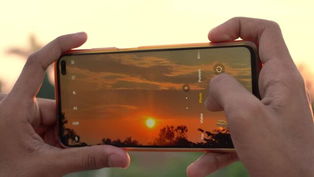 Taking a photo of a sunset with the mobile, clicking picture from phone