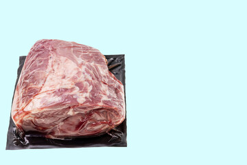 Close up view of vacuum packed piece of pork isolation on blue background. Food and health concept. 