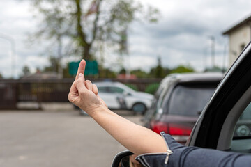 woman shows obscene gesture from a car, rude and furious driver giving middle finger to car behind