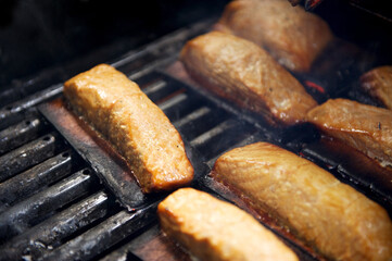 Salmon grilling on a BBQ with a cedar plank.