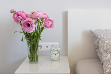 ranunculus azur deep pink in a vase on the bedside table in the bedroom