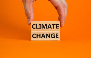 Climate change symbol. Wooden blocks with words 'Climate change' on beautiful orange background. Businessman hand. Business, ecological and climate change concept. Copy space.