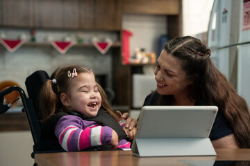 baby with disability and mother laughing and watching video online in tablet..