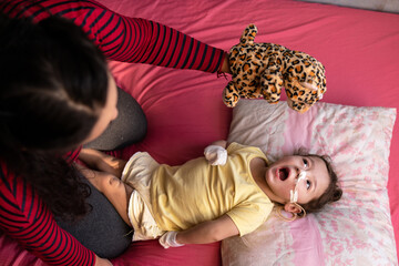 baby with disability having fun with jaguar puppet in bed. © Vergani Fotografia
