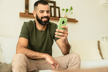 man with partial hand amputation smiling and looking at cell phone screen.